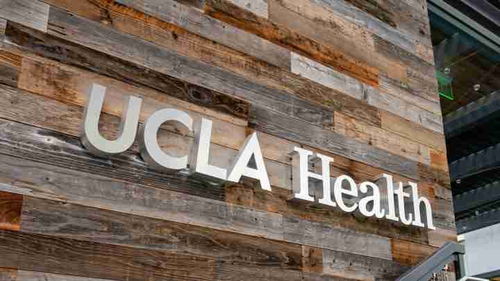 UCLA Health sign mounted on a rustic wood-paneled wall outside a building